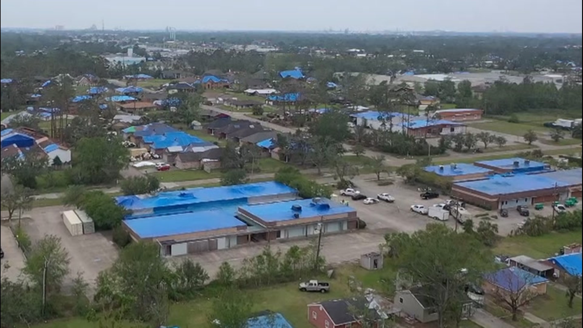 Drone video of blue tarps covering homes and businesses