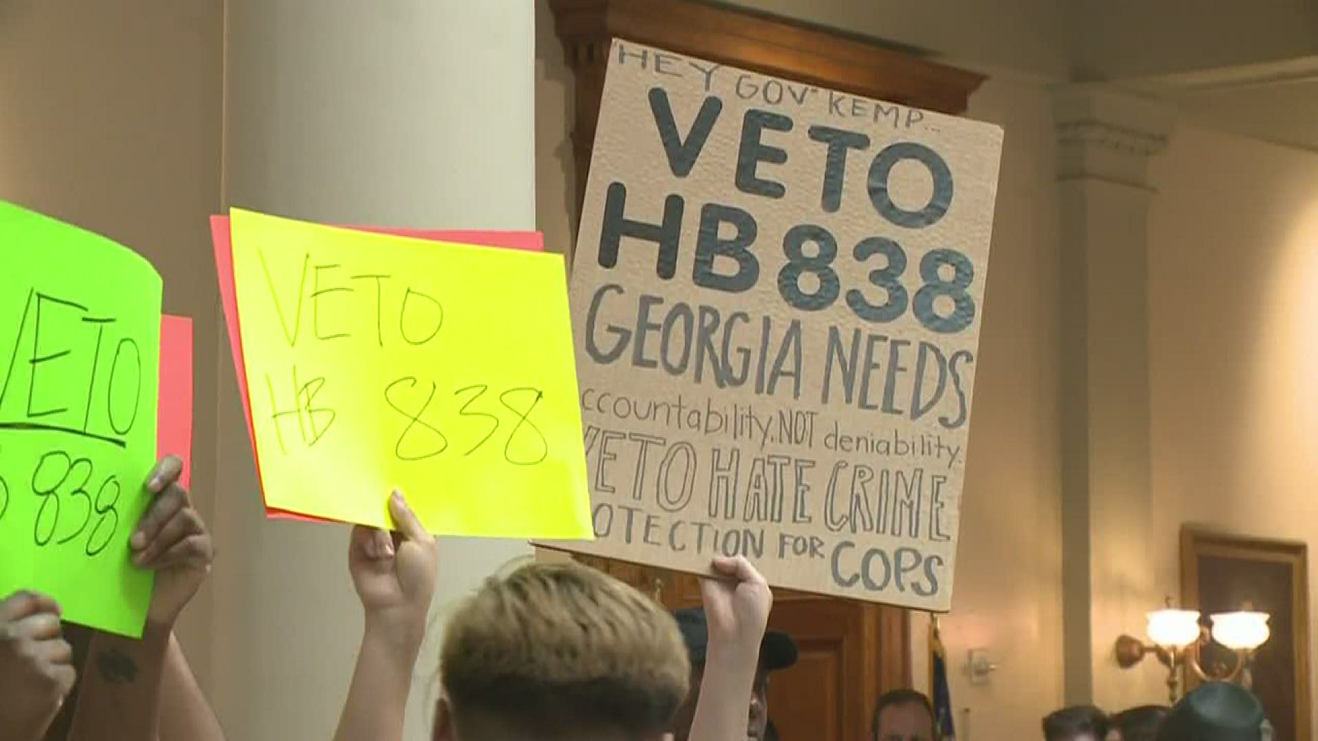 The demonstrators held signs and called for the governor to "do the right thing" on a separate bill, within moments of signing the hate crime legislation into law.